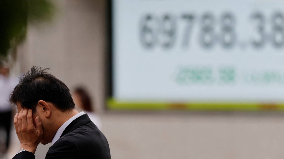 A pedestrian stands in front of a stock quotation board showing the Nikkei share average outside a brokerage in Tokyo, Japan, June 23, 2026.   REUTERS/Kim Kyung-Hoon