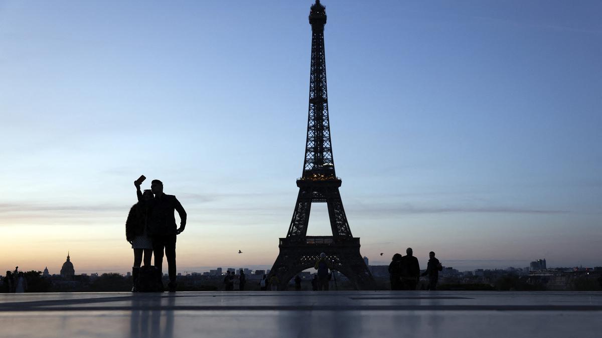 Two people take a selfie at the Trocadero in front of the Eiffel Tower at sunrise in Paris on April 6, 2026. (Kenzo Tribouillard/AFP/Getty Images/TNS)