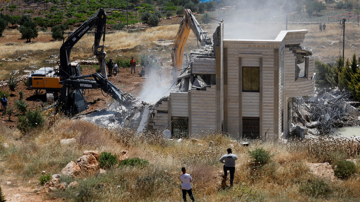 Palestinians observe, as heavy machinery demolishes a Palestinian house near Hebron, in the Israeli-occupied West Bank, June 8, 2026. REUTERS/Mussa Qawasma