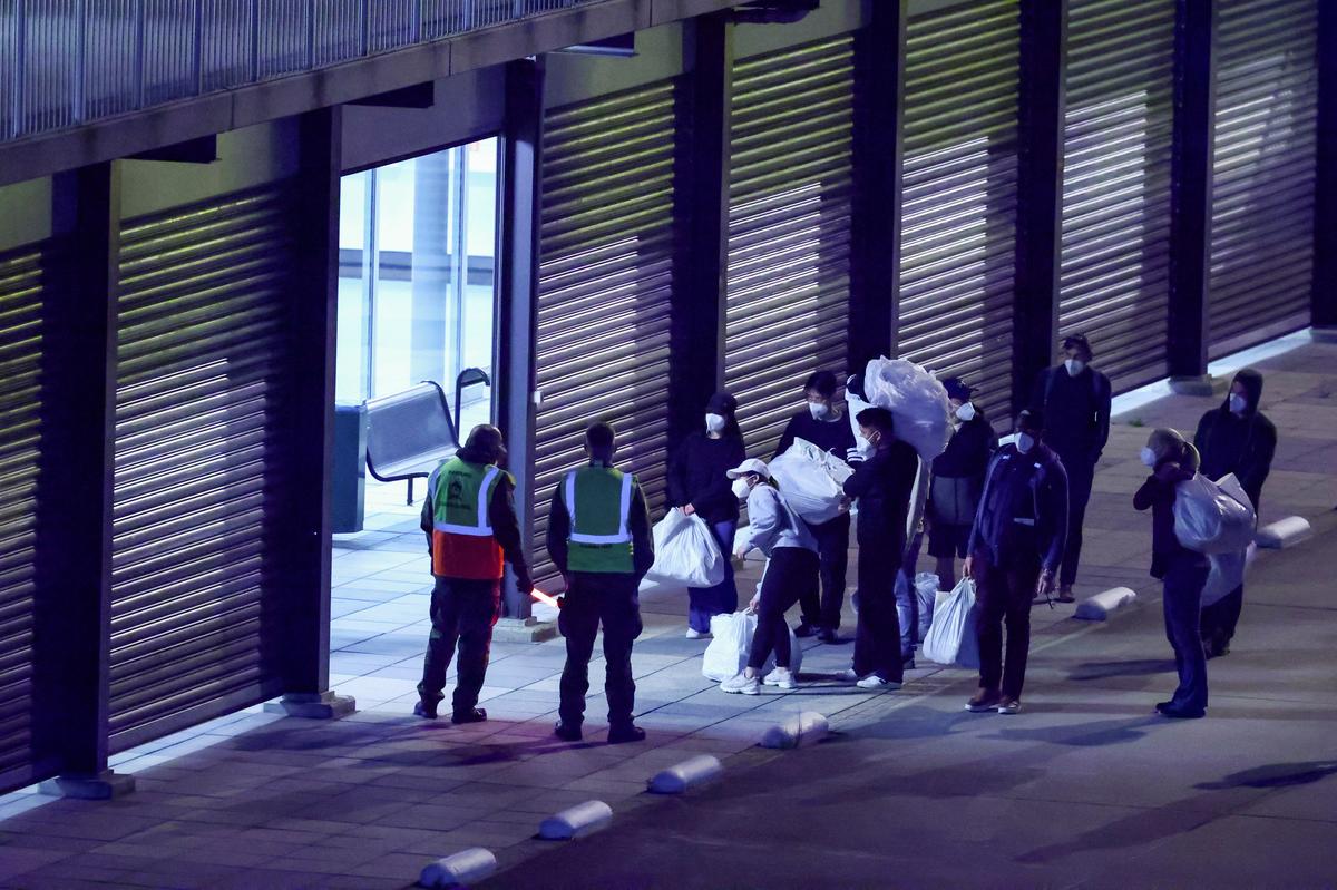 Passengers evacuated from the cruise ship MV Hondius, which was affected by a hantavirus outbreak, carry their belongings after disembarking at Eindhoven Air Base, Netherlands, May 12, 2026. REUTERS/Piroschka van de Wouw