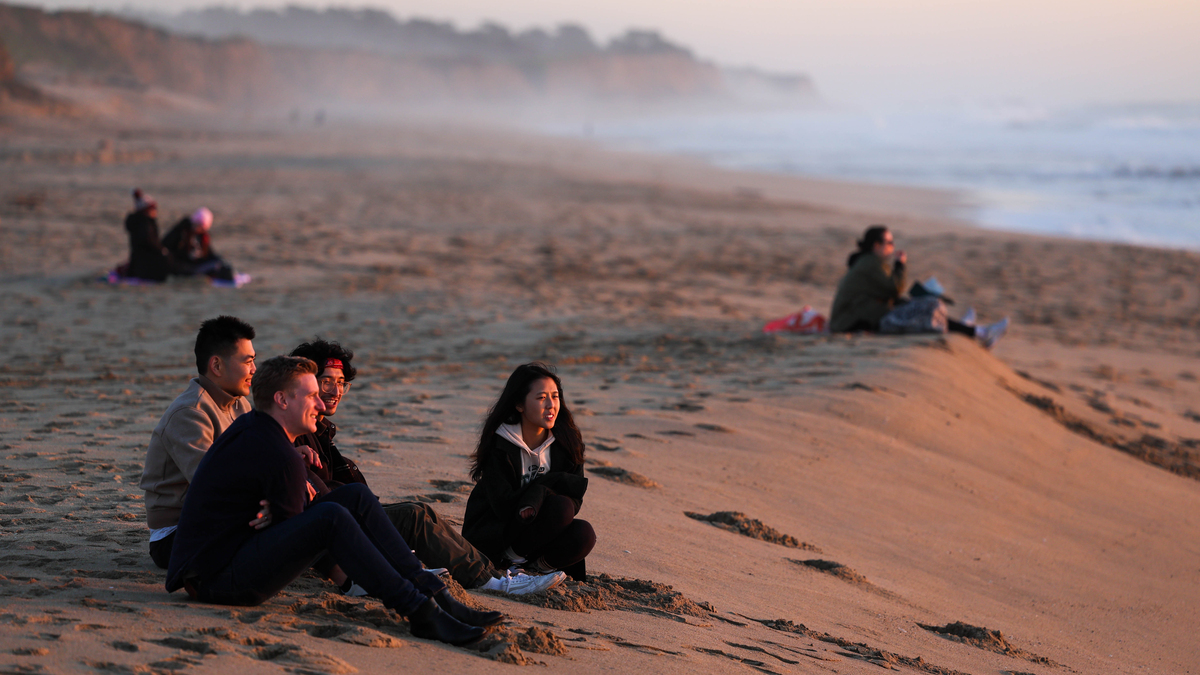 Beachgoers enjoy the weather and view as the sun sets in the horizon seen from Half Moon Bay State in Half Moon Bay, Calif., on Wednesday, Feb. 8, 2023. (Ray Chavez/Bay Area News Group)