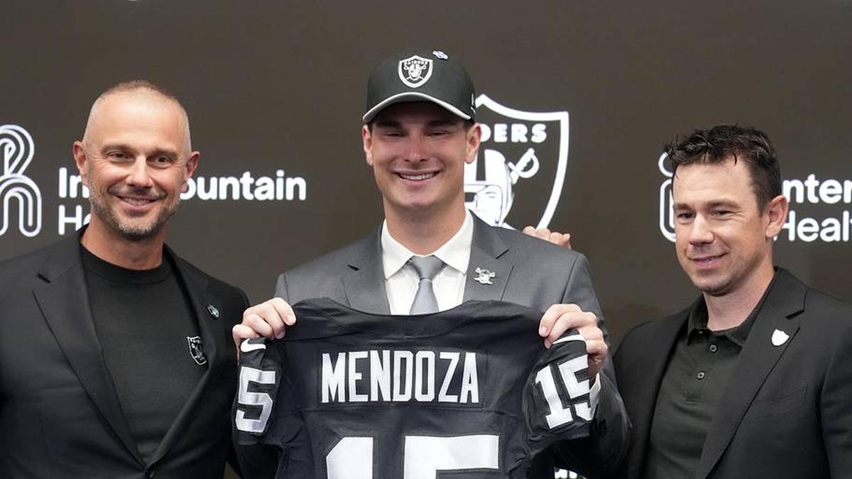  Apr 24, 2026; Henderson, NV, USA; Las Vegas Raiders quarterback Fernando Mendoza (center) poses with jersey at introductory press conference at Intermountain Health Performance Center flanked by general manager John Spytek (left) and head coach Klint Kubiak after being selected as the No. 1 pick in the 2026 NFL Draft. Mandatory Credit: Kirby Lee-Imagn Images | Kirby Lee-Imagn Images 