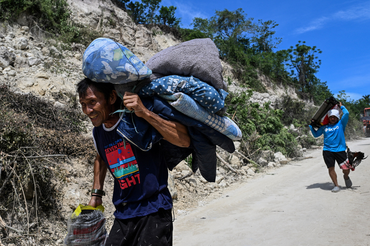 People living on the mountainside carry their belongings as they evacuate after a landslide following the magnitude 7.8 quake in Barangay Kapatan, Glan, Sarangani province, southern Philippines, June 10, 2026. REUTERS/Noel Celis