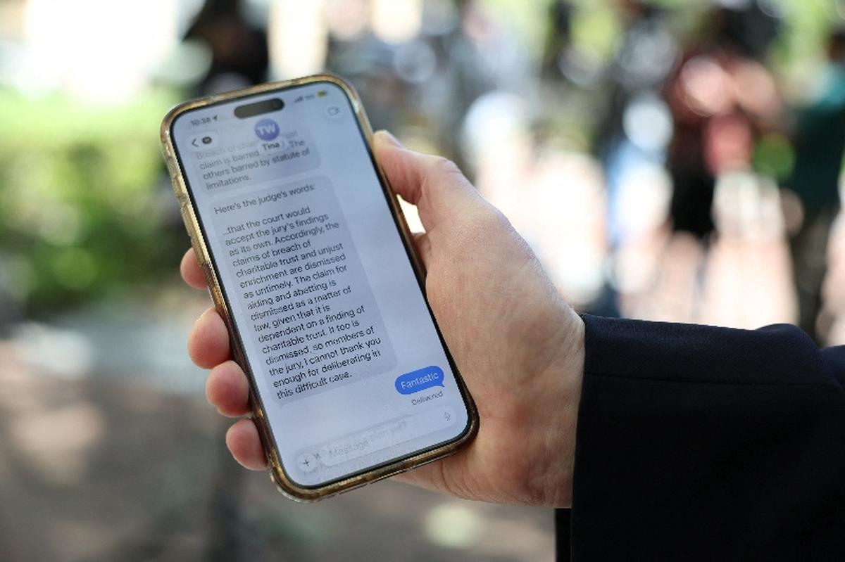 Sam Singer, president of Singer Associates Public Relations, poses with a phone featuring a text message related to the trial in Elon Musk's lawsuit over OpenAI's for-profit conversion, outside the federal courthouse, in Oakland, California, U.S., May 18, 2026. REUTERS/Manuel Orbegozo