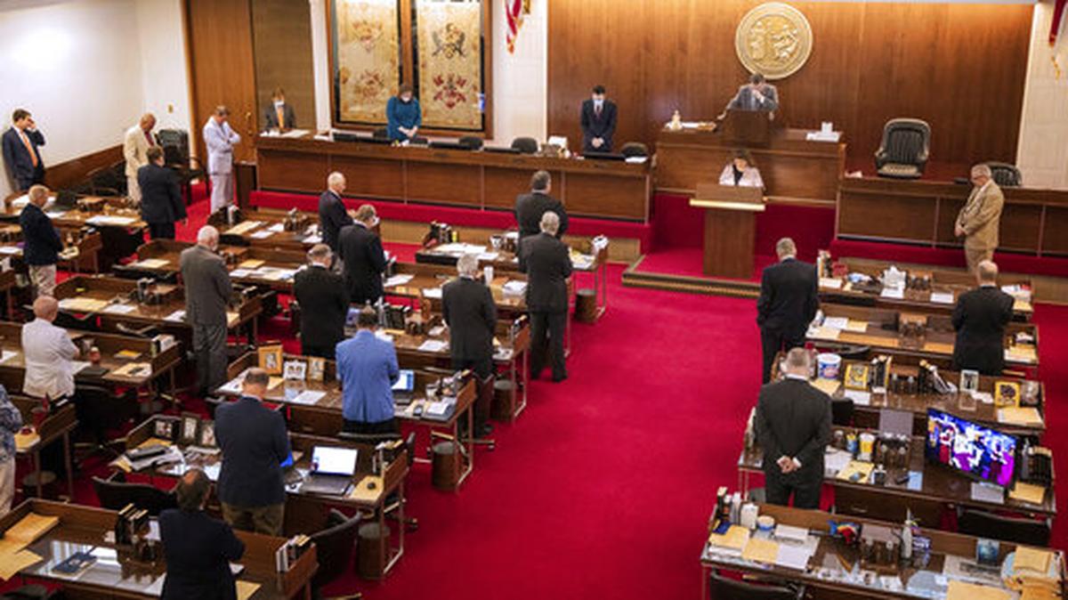 Members of the North Carolina House of Representatives stand in prayer before finalizing versions of a bill allocating $3.5 billion in new federal money for COVID-19 relief, on Saturday, May 2, 2020, in the North Carolina General Assembly building in Raleigh, N.C.