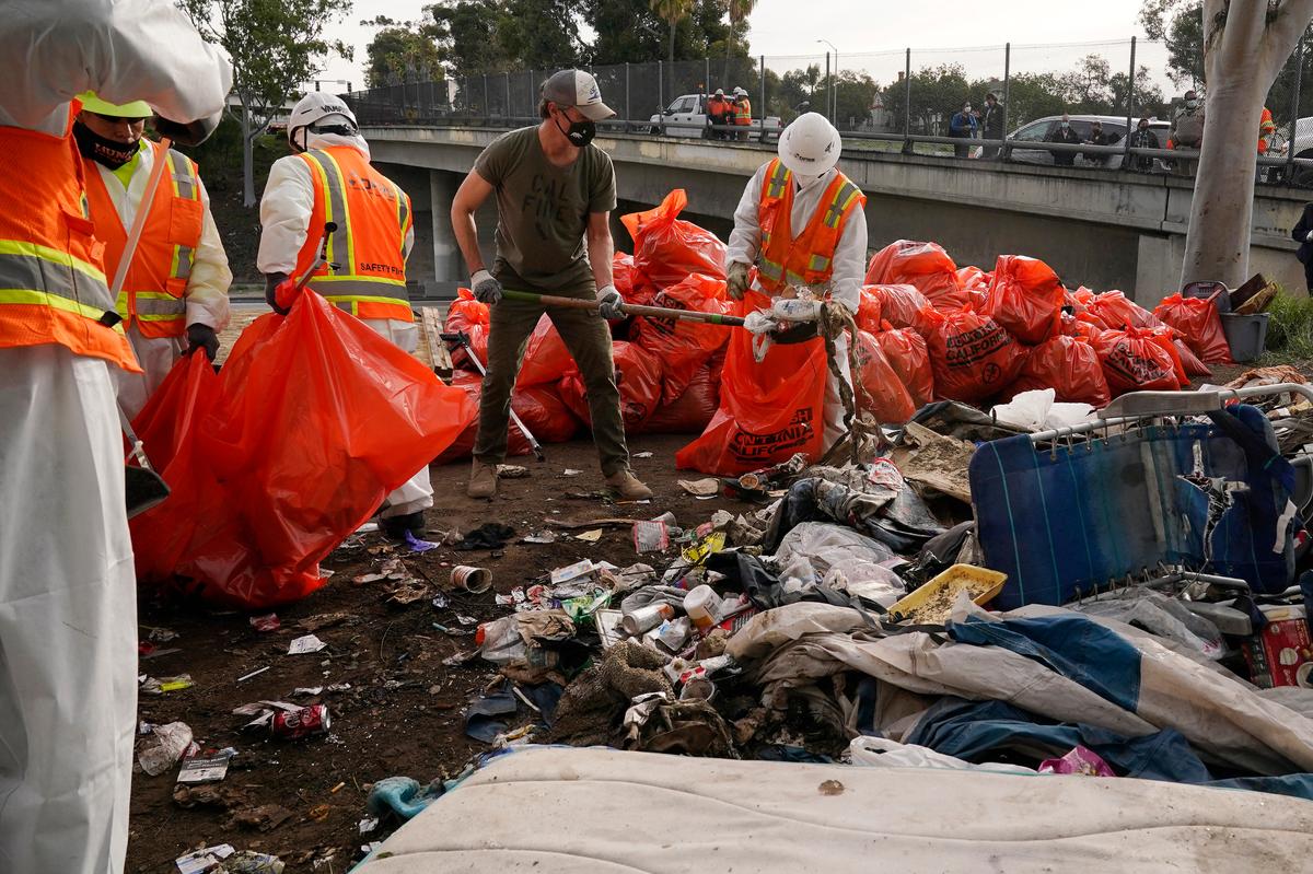 Gov. Gavin Newsom, center, helps clean a homeless encampment alongside a freeway in January in San Diego. The issue is considered a serious problem by nearly two-thirds of California voters.