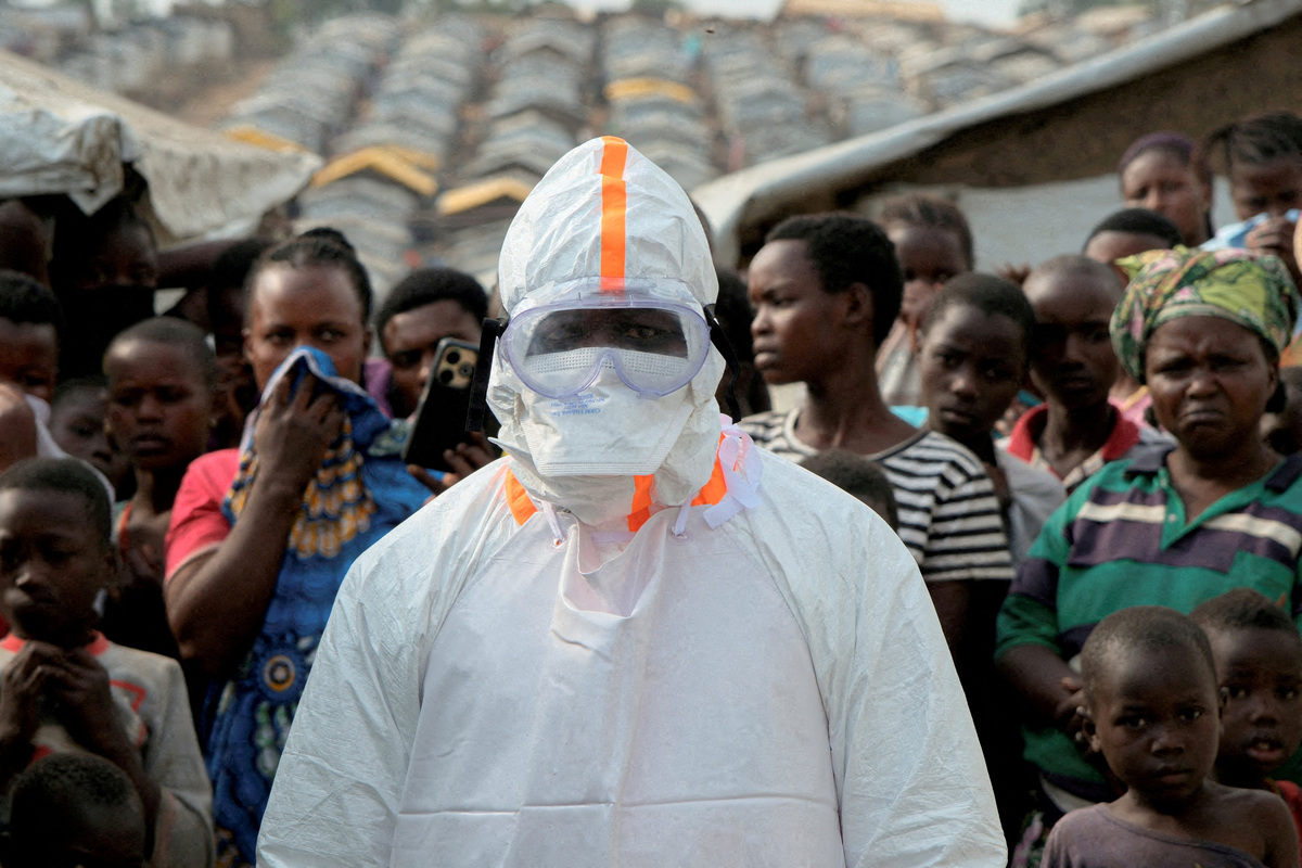 FILE PHOTO: A health worker in personal protective equipment stands near displaced people waiting for the burial of suspected Ebola victims at the Kigonze displaced persons camp, one month after an outbreak was declared, in Bunia, eastern Democratic Republic of Congo, June 18, 2026. REUTERS/Gradel Muyisa Mumbere/File Photo