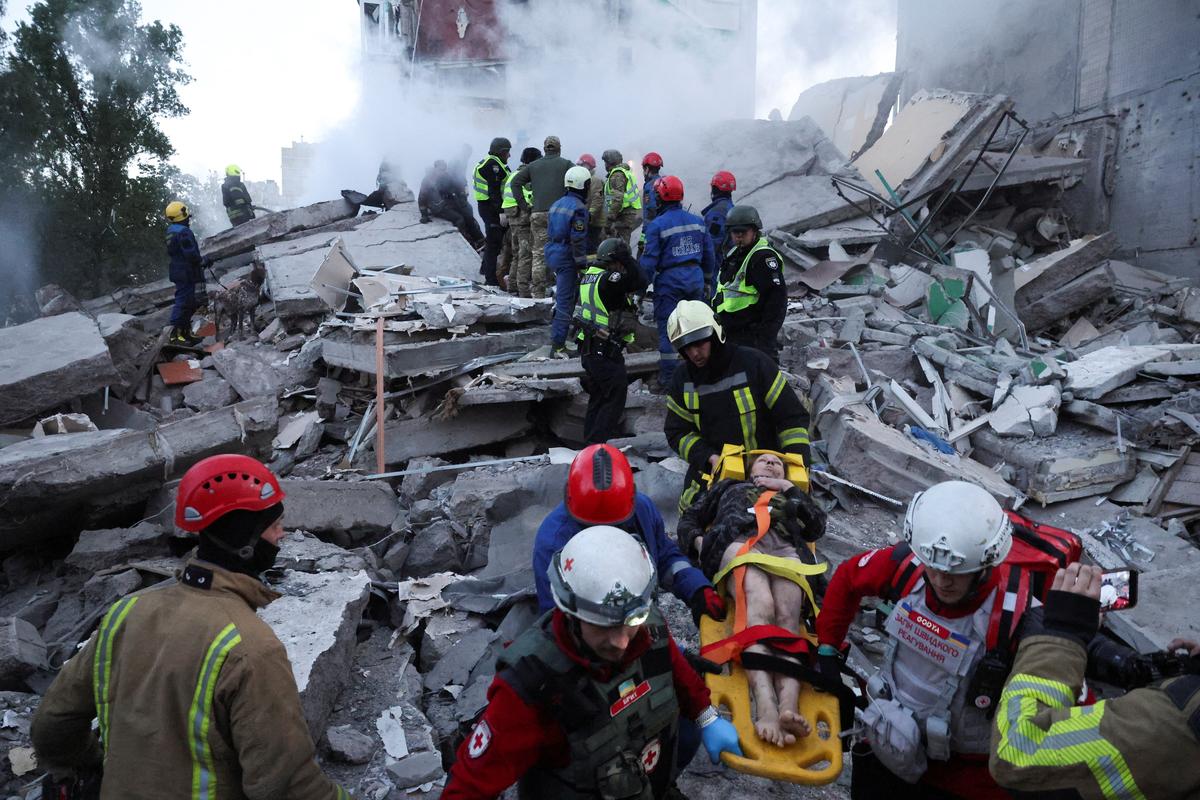 Rescuers evacuate an injured woman from an apartment building damaged during Russian missile and drone strikes, amid Russia's attack on Ukraine, in Kyiv, Ukraine, May 14, 2026. REUTERS/Thomas Peter