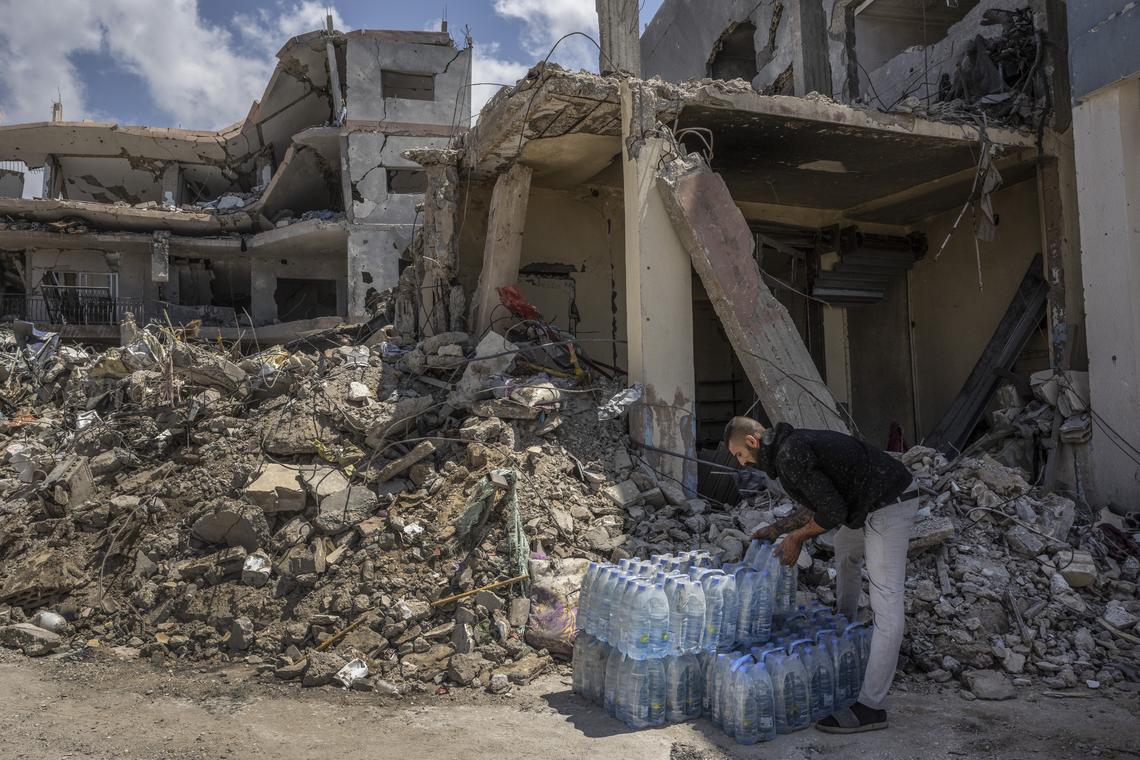 A man stacks bottles of water in the ruins of the southern Lebanese village of Mansouri, on Tuesday, April 21, 2026. The U.S. State Department will host a second round of ambassador-level talks between Israel and Lebanon, which are in a cease fire, on Thursday, the department said. (David Guttenfelder/The New York Times)