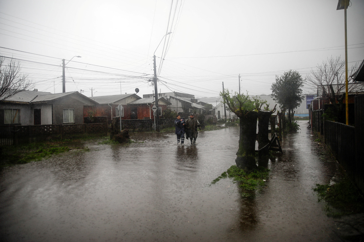Residents walk along a flooded street, after heavy rain fall during a weather front caused flooding and led the Chilean authorities to declare a preventive state of emergency at the start of the week, in Arauco, Chile, July 16, 2026. REUTERS/Juan Gonzalez