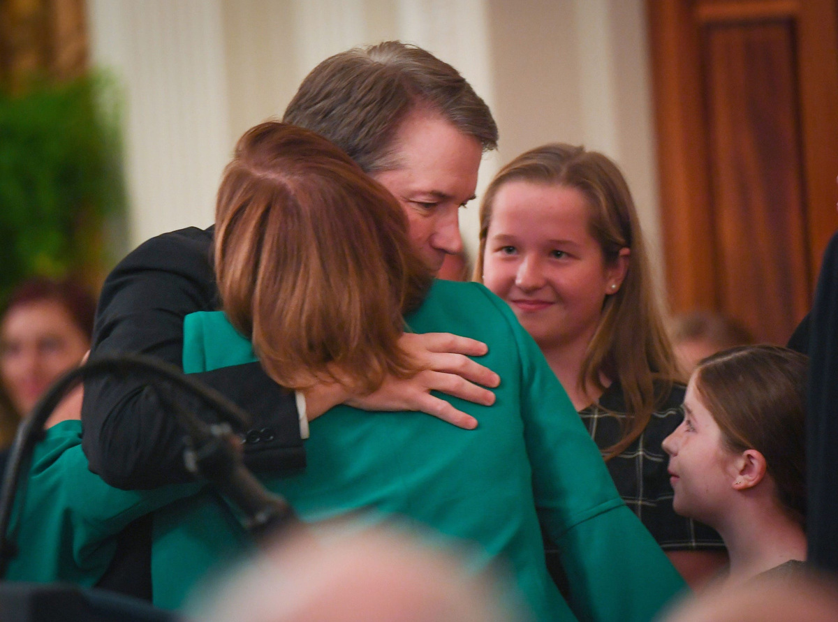 Newly confirmed Supreme Court Justice Brett Kavanaugh hugs his wife Ashley Kavanaugh alongside their daughters Liza Kavanaugh and Margaret Kavanaugh in the East Room of the White House in 2018.