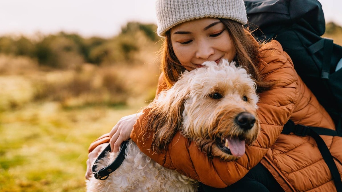 Young Asian woman in loving embrace with her dog in nature.