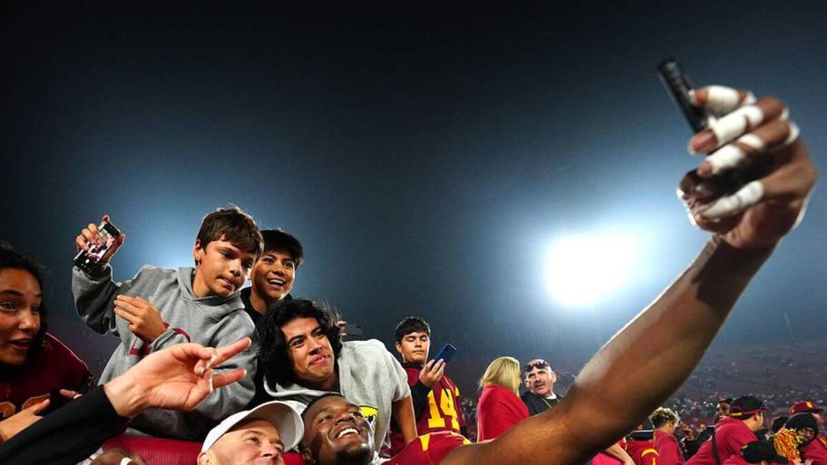  Nov 29, 2025; Los Angeles, California, USA; Southern California Trojans head coach Lincoln Riley (right) and defensive tackle Jahkeem Stewart (4) pose with fans after the game against the UCLA Bruins at United Airlines Field at Los Angeles Memorial Coliseum. Mandatory Credit: Kirby Lee-Imagn Images | Kirby Lee-Imagn Images 