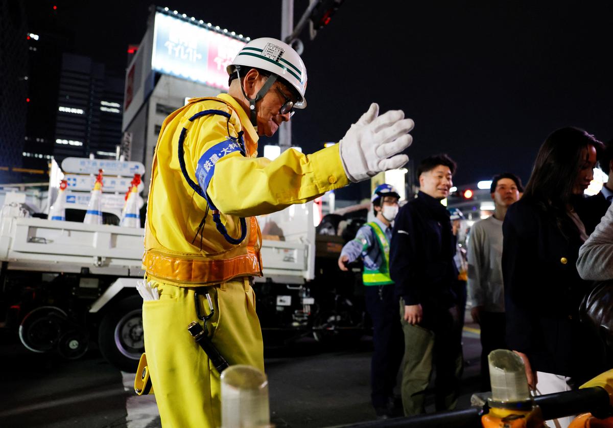Shuetsu Sato, a security guard whose handmade duct-tape signs have gained widespread recognition, directs pedestrians near a construction site outside Shinjuku Station's east exit, in Tokyo, Japan, May 8, 2026.  REUTERS/Kim Kyung-Hoon