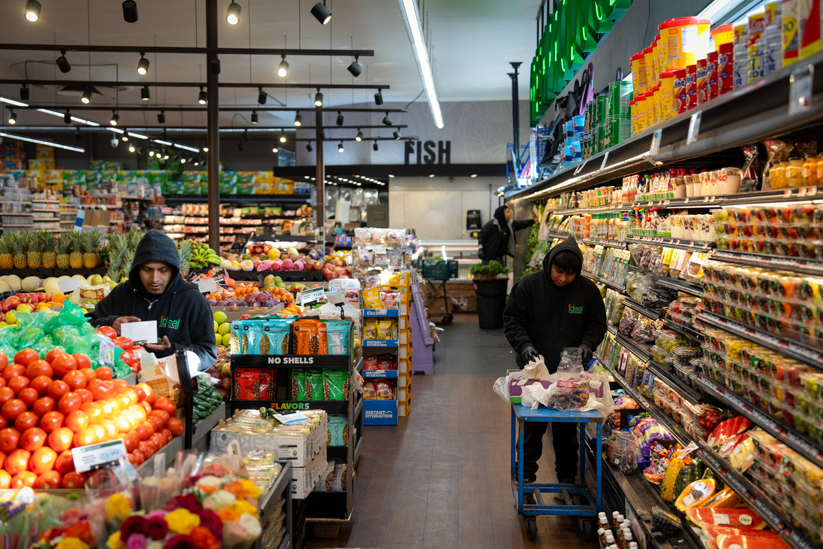 FILE -- Grocery workers stocking items in Brooklyn, April 16, 2026. Households are facing renewed cost-of-living pressures as inflation rises and central banks keep interest rates elevated. (Vincent Alban/The New York Times)