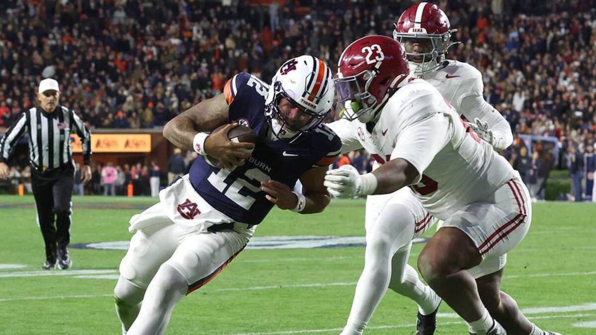  Nov 29, 2025; Auburn, Alabama, USA; Auburn Tigers quarterback Ashton Daniels (12) runs with the ball against Alabama Crimson Tide defensive lineman James Smith (23) during the first half at Jordan-Hare Stadium. Mandatory Credit: John Reed-Imagn Images | John Reed-Imagn Images 