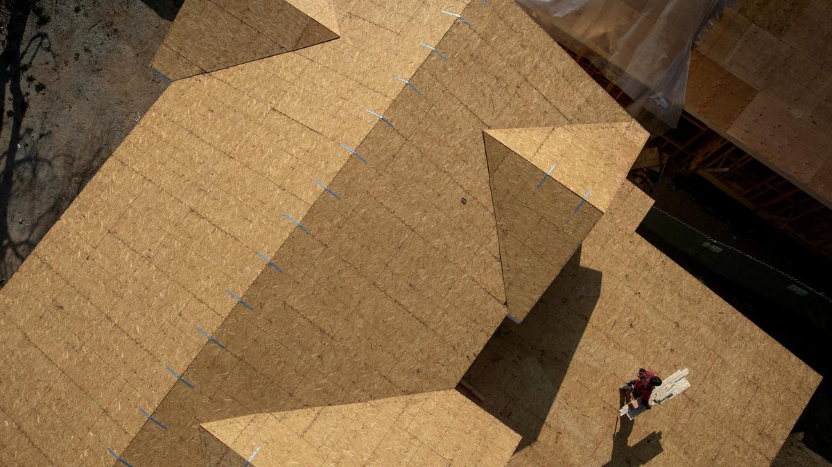 A worker carries lumber on the roof of a home under construction along Laurel Drive on April 30, 2026, in Altadena, California. (Eric Thayer/Los Angeles Times/TNS)