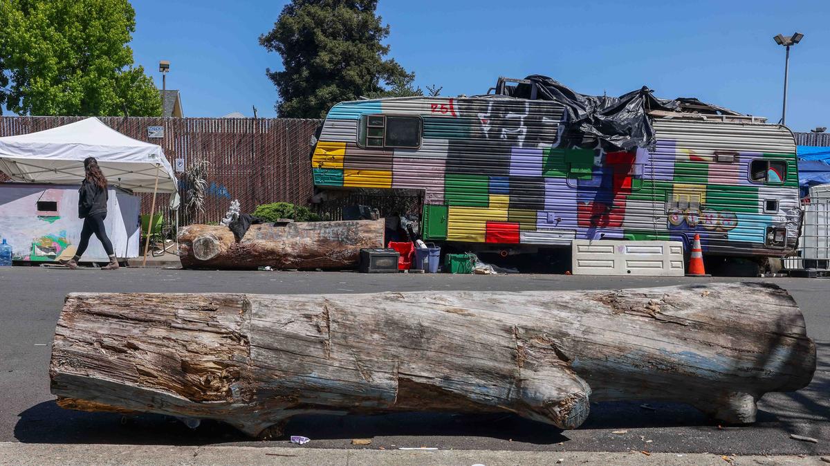 Large tree logs sit along a curbside paralleled to a line of RVs parked at a homeless encampment on Poplar Street in West Oakland, Calif., on Wednesday, April 29, 2026. The logs were placed a few years ago to prevent unhoused vehicles from parking in front of businesses. (Ray Chavez/Bay Area News Group/TNS)