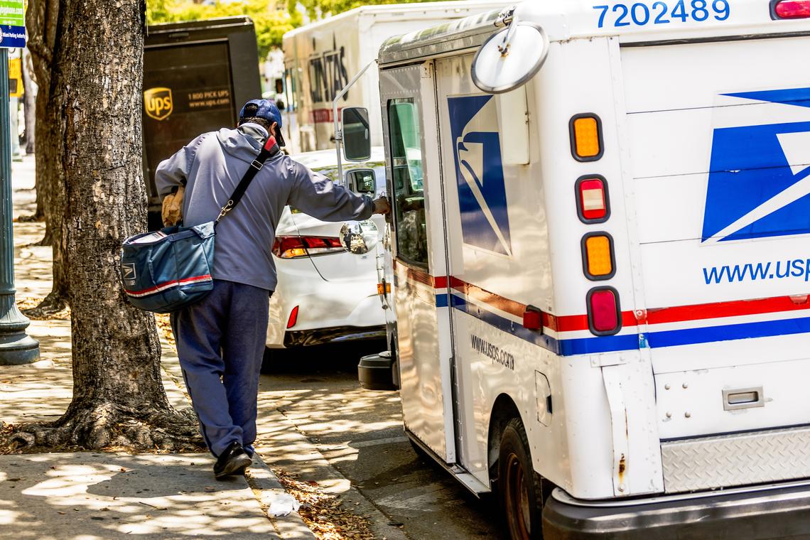 FILE -- A U.S. Postal Service worker in Miami, on April 28, 2025. On April 9, 2026, the Postal Service proposed increasing the costs of stamps by another 5 percent and said that it would temporarily suspend some payments to a government retirement fund. (Scott McIntyre/The New York Times)