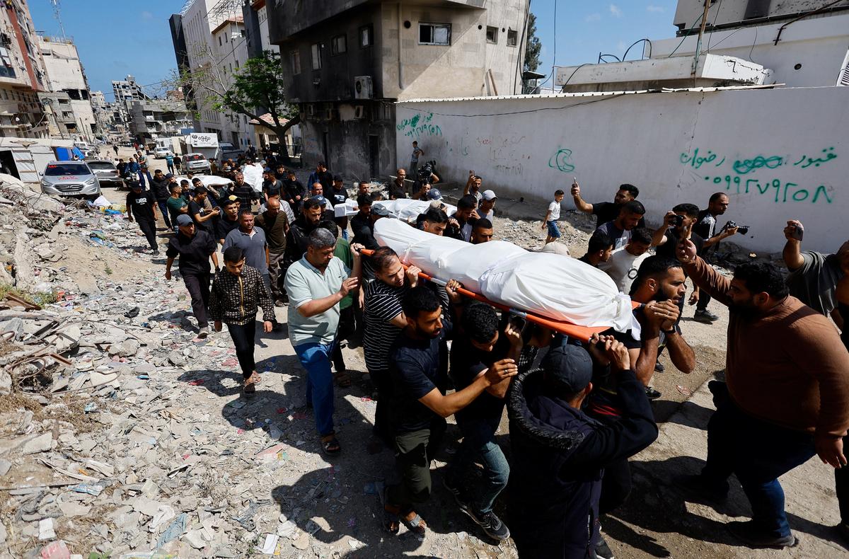 People carry bodies identified by mourners as Hamas' military wing commander Mohammad Odeh, who was killed in an Israeli strike on Tuesday, and his wife and children, during a funeral, in Gaza City, May 27, 2026. REUTERS/Mahmoud Issa