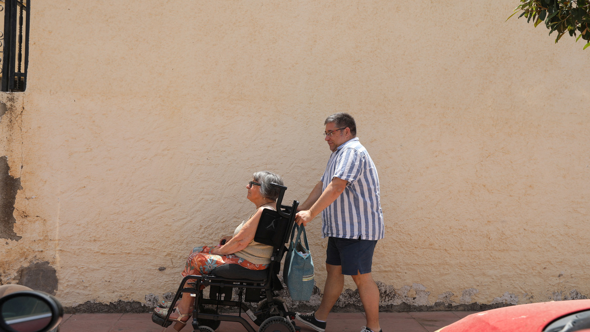 Daniel Northover, 53, who moved from Britain to Spain to care for his mother after her husband's death, takes his mother Carole Bentley, 80, for a walk in her wheelchair along a street in the village of Turre, Almeria, Spain, June 18, 2026. REUTERS/ Loyola Perez de Villegas Muniz