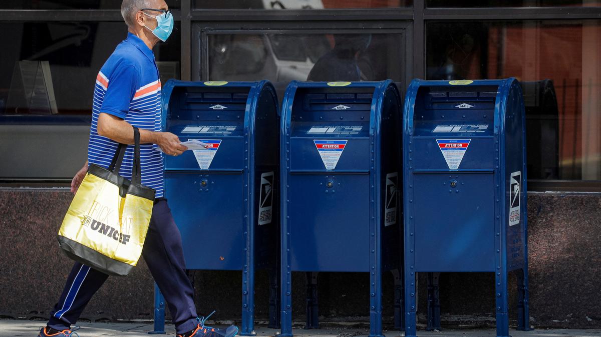 FILE PHOTO: A man carries letters into a United States Postal Service (USPS) post office in the Brooklyn borough of New York City, U.S., August 21, 2020. REUTERS/Brendan McDermid/File Photo