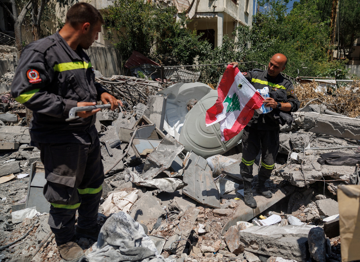 A member of the government-run Lebanese Civil Defense, the country's primary firefighting, first aid, and rescue force, holds a Lebanese flag salvaged from the rubble while inspecting their headquarters in Nabatieh, Lebanon, June 17, 2026, following the deal between the United States and Iran. The headquarters was destroyed in an Israeli airstrike in May. REUTERS/Zohra Bensemra