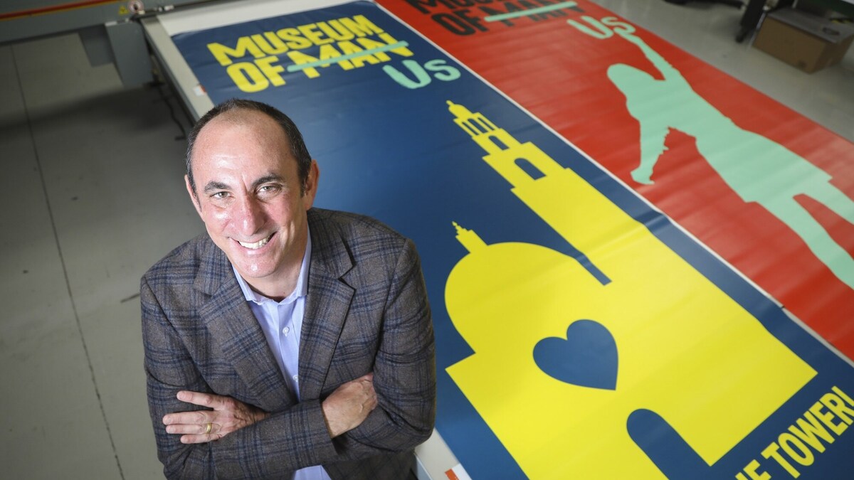 Micah Parzen, CEO, Museum of Us, poses for photos with new banners at Dimensional Silk Screen on Thursday, July 30, 2020 in San Diego, CA. The banners will announce the name change from the Museum of Man to the Museum of Us. (Eduardo Contreras / The San Diego Union-Tribune)