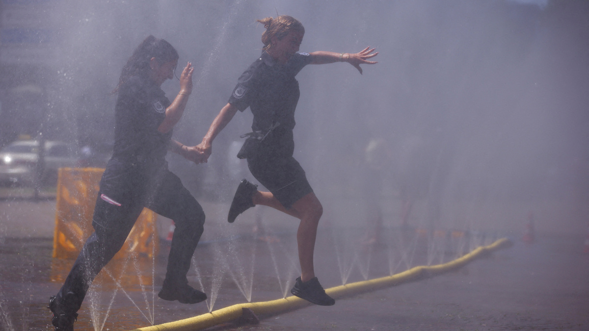 FILE PHOTO: Women run through a water spray from a public outdoor sprinkler system to alleviate high temperatures at Rudolfplatz square, amid a heatwave in Cologne, Germany, June 25, 2026. REUTERS/Thilo Schmuelgen/File Photo