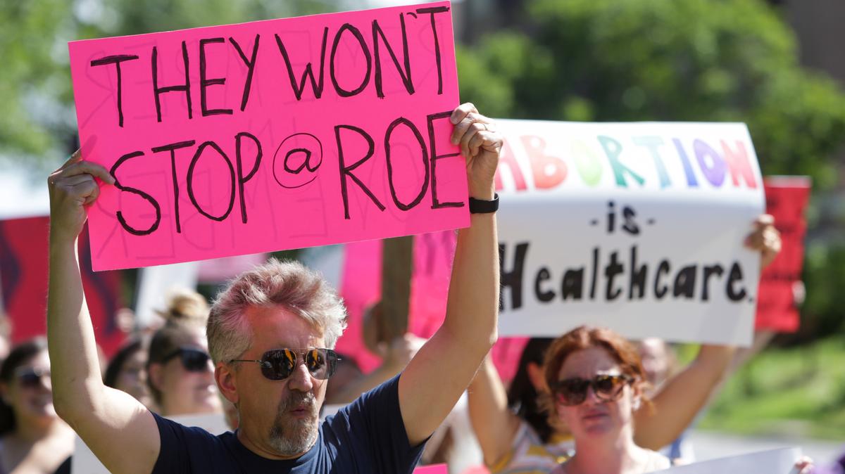Un hombre sostiene un cartel a favor del derecho al aborto mientras los miembros de la comunidad caminan por el Parque Vander Veer durante una marcha tras la decisión de la Corte Suprema de revocar Roe vs. Wade, el 26 de junio de 2022, en Davenport, Iowa. Los demócratas y sus grupos alineados recaudaron más de $80 millones en la semana posterior a que la Corte Suprema eliminó el derecho constitucional de una mujer a abortar. La avalancha de efectivo ofrece una de las primeras señales tangibles de cómo el fallo puede energizar a los votantes. (Nikos Frazier/Quad City Times vía AP)