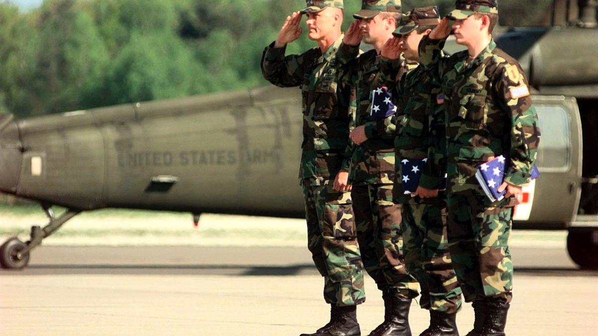 Staff Sgt. Chris Stone (L), Staff Sgt. Andrew Ramirez (C) and Specialist Steven Gonzales, the three soldiers from the 1st Infantry Division who were captured by Yugoslavian forces, salute the colors after returning to Germany with the Rev. Jesse Jackson who was instrumental in their release. File Photo by Ken Bergmann/USAF 