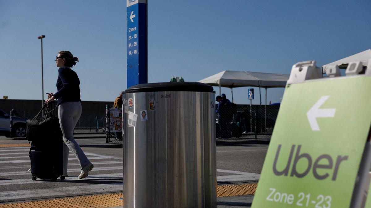 A traveler walks into the Uber pickup zone at the Los Angeles International Airport's LAX-it pick up terminal in Los Angeles, California, U.S., March 10, 2026.  REUTERS/Caroline Brehman