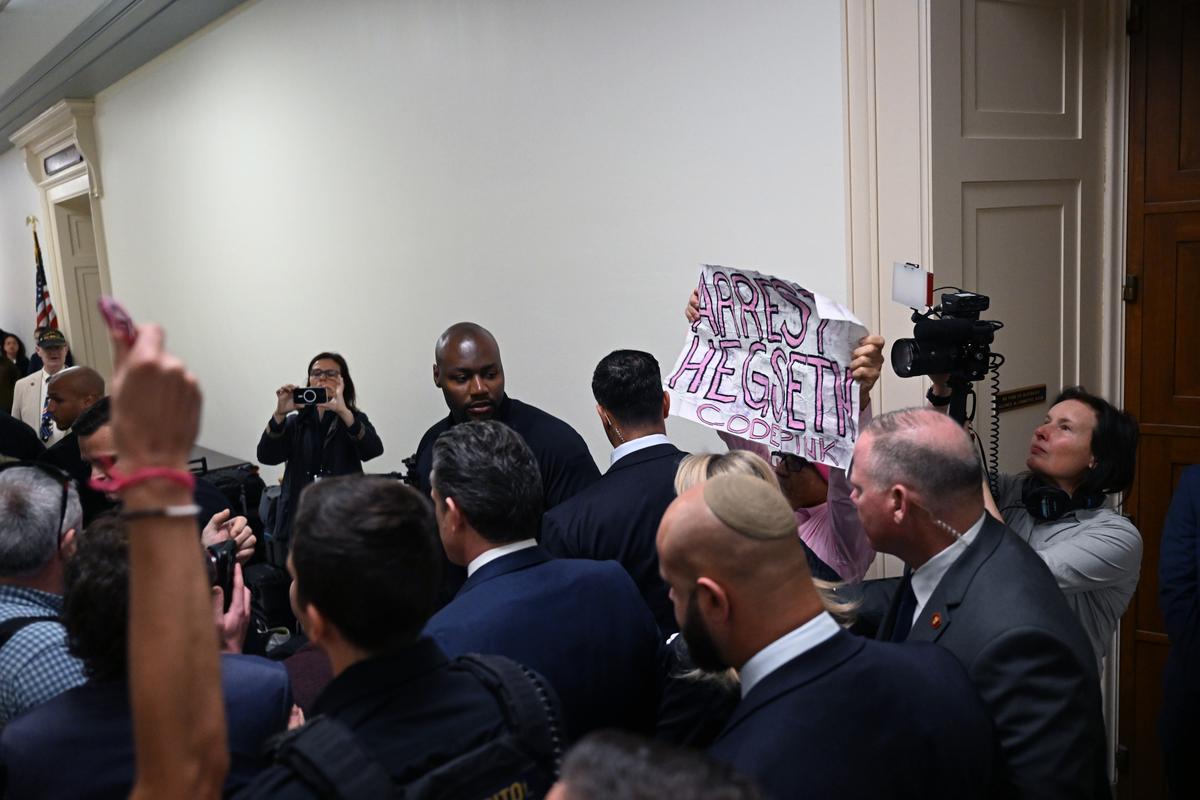 A protester holds up a sign as Defense Secretary Pete Hegseth arrives at a hearing before the House Armed Services Committee in Washington on Wednesday morning, April 29, 2026. (Kenny Holston/The New York Times)