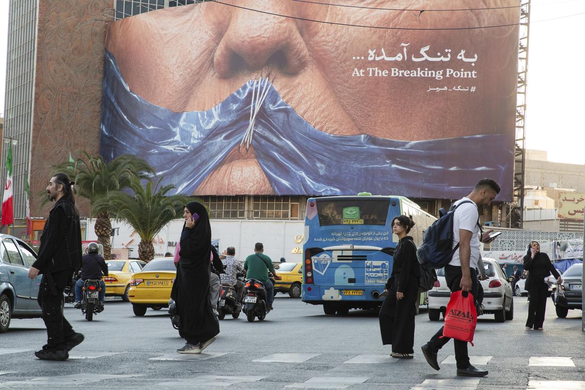 People walk past a new billboard depicting the closure of the Strait of Hormuz in Valiasr Square, Tehran, Iran, May 2, 2026. President Donald Trump's predictions of a relatively short-term conflict with minimal economic consequences appear to be crumbling. (Arash Khamooshi/The New York Times)