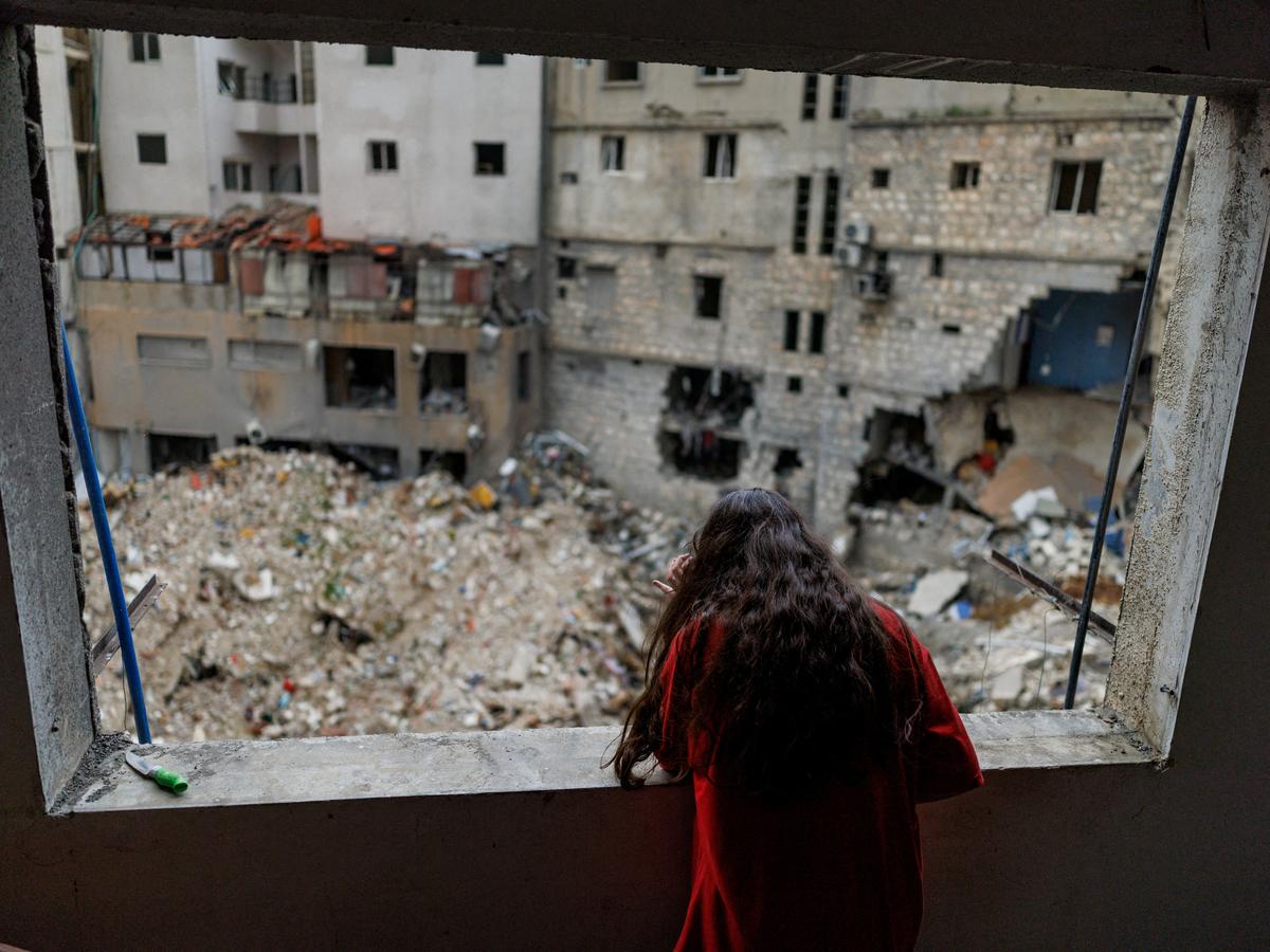 FILE PHOTO: Alaa Dahnoun, 12, who said she survived an Israeli strike that forced her to flee with her parents to Beirut, looks out through her apartment's damaged window after a 10-day ceasefire between Lebanon and Israel went into effect, in Nabatieh, Lebanon, April 18, 2026. REUTERS/Zohra Bensemra/File Photo