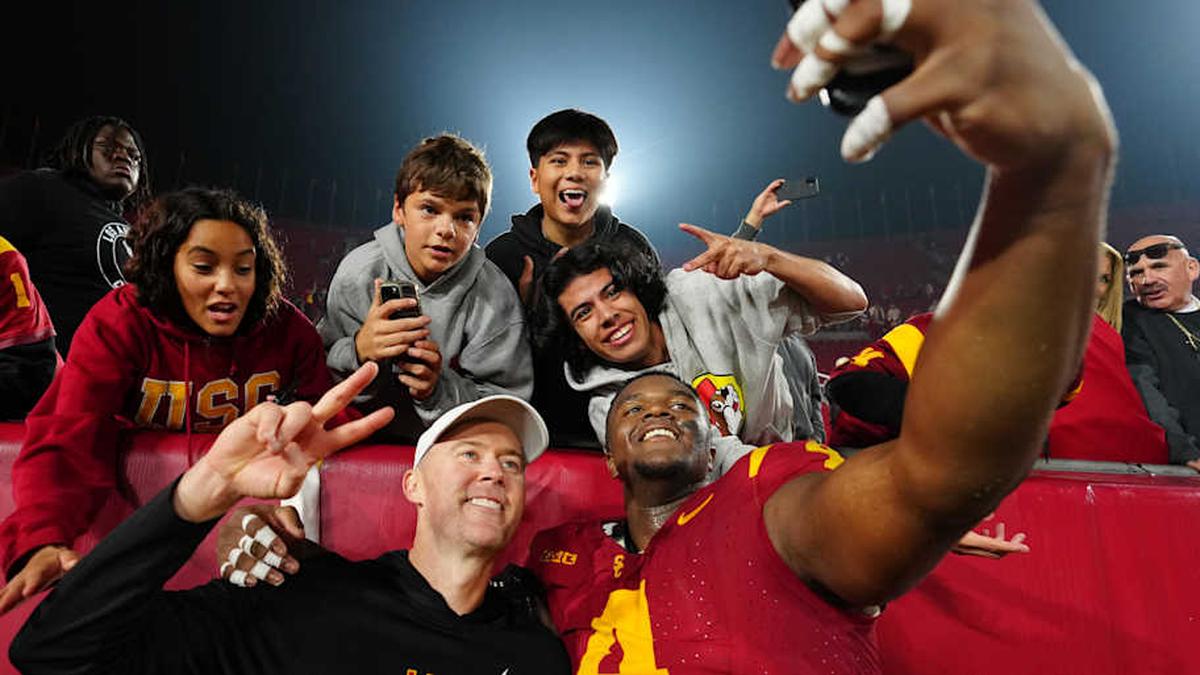 Nov 29, 2025; Los Angeles, California, USA; Southern California Trojans head coach Lincoln Riley (right) and defensive tackle Jahkeem Stewart (4) pose with fans after the game against the UCLA Bruins at United Airlines Field at Los Angeles Memorial Coliseum. Mandatory Credit: Kirby Lee-Imagn Images | Kirby Lee-Imagn Images 
