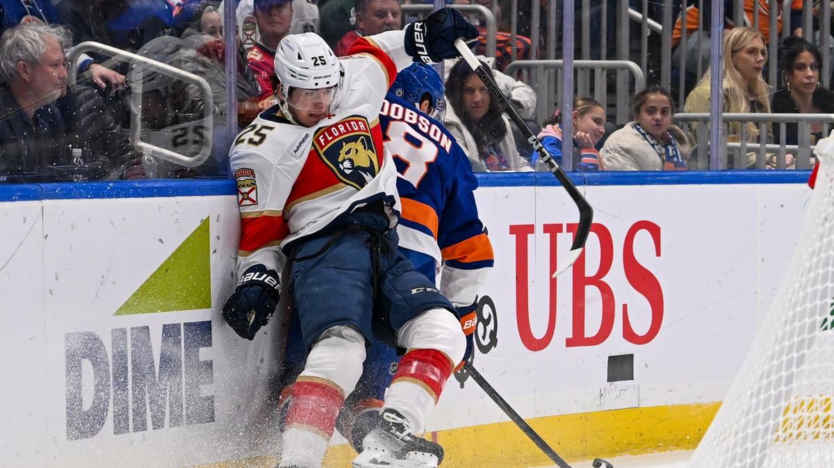 Oct 26, 2024; Elmont, New York, USA; Florida Panthers right wing Mackie Samoskevich (25) and New York Islanders defenseman Noah Dobson (8) collide along the boards during the first period at UBS Arena. Mandatory Credit: Dennis Schneidler-Imagn Images