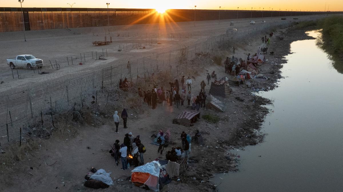 A drone view shows the sun rise over migrants as they stand along the U.S. side of the Rio Grande while the U.S. 5th Circuit Court of Appeals hears oral arguments on Texas' motion to lift a block on its SB4 immigration law that would allow state officials to arrest migrants suspected of being in the country illegally, in El Paso, Texas, U.S., March 22, 2024. REUTERS/Adrees Latif