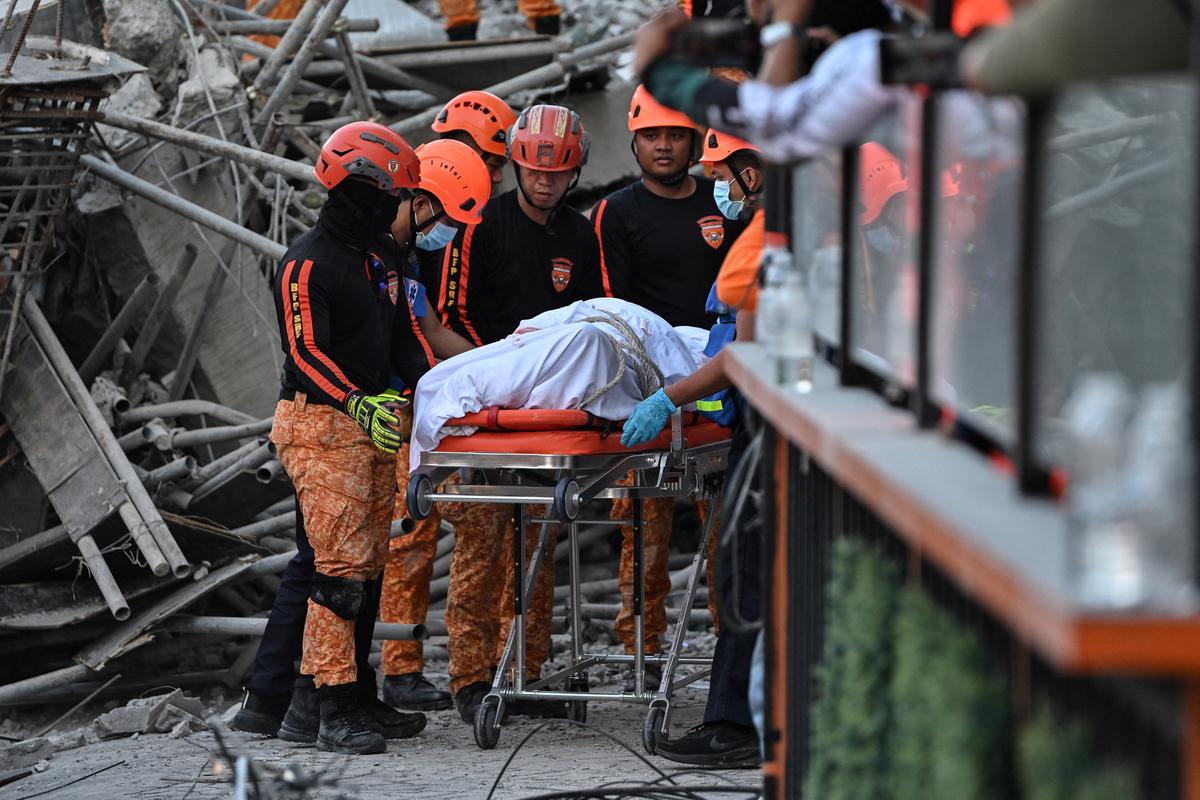 Rescue workers retrieve the body of a victim among debris as a nine-story building under construction collapsed in Balibago, Angeles City, Pampanga, Philippines, May 24, 2026. REUTERS/Noel Celis