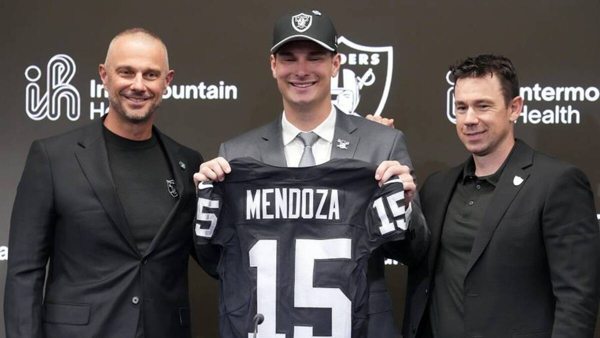  Apr 24, 2026; Henderson, NV, USA; Las Vegas Raiders quarterback Fernando Mendoza (center) poses with jersey at introductory press conference at Intermountain Health Performance Center flanked by general manager John Spytek (left) and head coach Klint Kubiak after being selected as the No. 1 pick in the 2026 NFL Draft. Mandatory Credit: Kirby Lee-Imagn Images | Kirby Lee-Imagn Images 