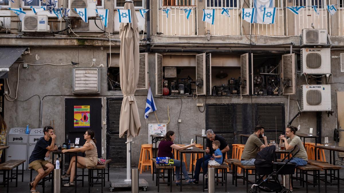 People sit at an outdoor restaurant where Israeli flags are displayed, amid the ongoing conflict between Hamas and Israel, in Tel Aviv, Israel, July 12, 2024. REUTERS/Eloisa Lopez