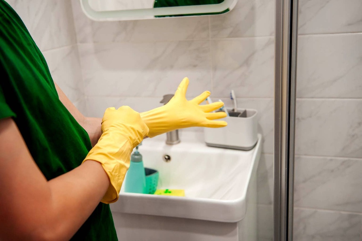  Person putting on yellow rubber gloves.