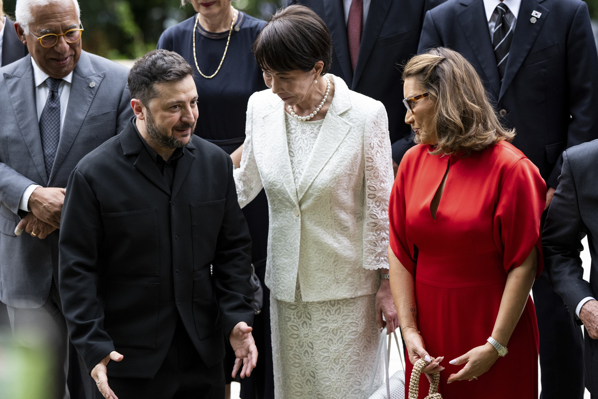 President Volodymyr Zelenskyy of Ukraine, left, speaks with Prime Minister Sanae Takaichi, center, and Rosângela da Silva, Brazil's first lady, as they prepare for a group photo ahead of a cultural performance at the G7 Summit in Evian-les-Bains, France, June 16, 2026. (Haiyun Jiang/The New York Times)