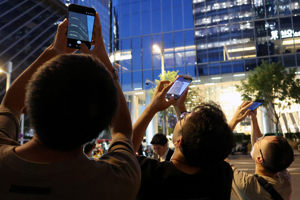 FILE PHOTO: File Photo: People point their mobile phones at CITIC Tower, also known as China Zun, where damage is visible on a high floor of the exterior, in Beijing, China June 26, 2026. REUTERS/Maxim Shemetov/File Photo/File Photo