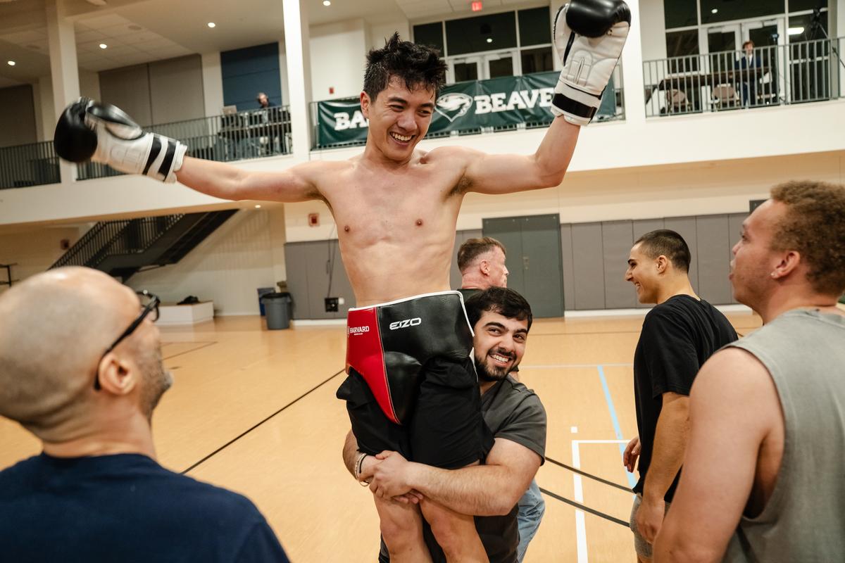 Aram Bagdasarian, the president of the Harvard Boxing Club, hoists Ryan Jiang after the freshman won his bout for Harvard University during a boxing exhibition at Babson College in Wellesley, Mass., April 24, 2026. Boxing clubs at Harvard and other colleges are drawing new members as students look for a real-life connection. (Sophie Park/The New York Times)