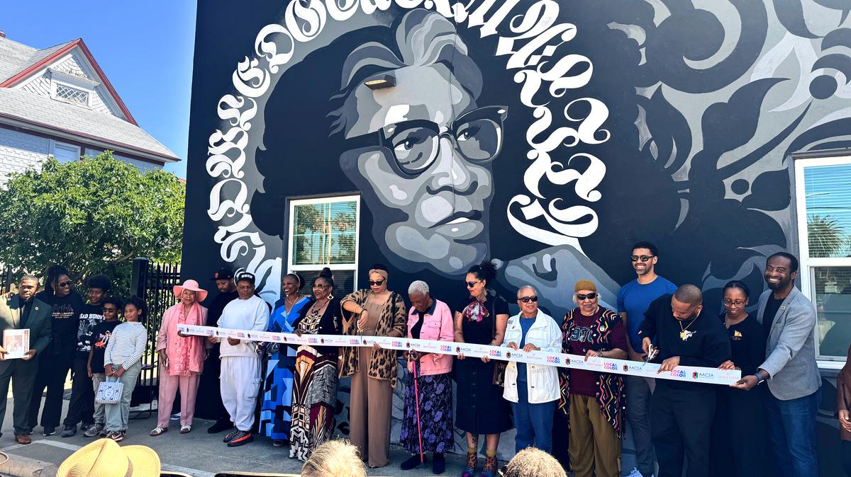 A group of people including Inez Jackson's family members and artist Ian Young cut the ribbon on a new mural honoring San Jose's first Black postal worker at the African American Community Service Agency on Saturday, May 16, 2026. (Sal Pizarro/Bay Area News Group)
