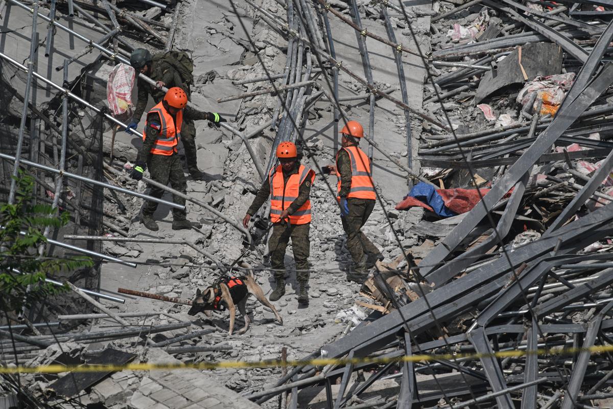 Rescue workers use a search-and-rescue dog as they look for trapped survivors among the debris of a collapsed nine-storey building under construction in Balibago, Angeles City, Pampanga, Philippines, May 25, 2026. REUTERS/Noel Celis