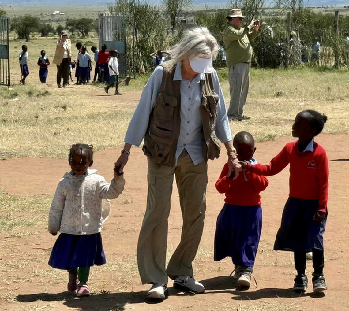  Children at the Mara Daima Academy in Kenya delighted in holding hands with visitors during recess: She Buys Travel writer Christine Tibbetts in foreground and editor Cindy Richards at the gate. Photo credit: Kim Schneider 