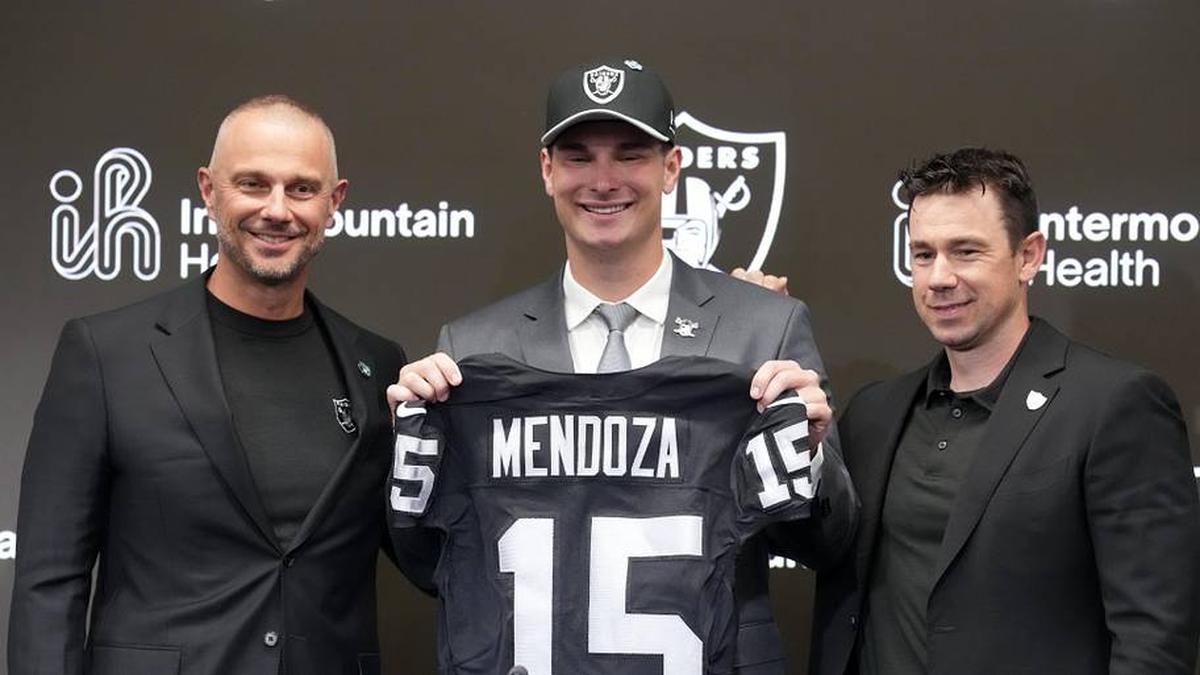  Apr 24, 2026; Henderson, NV, USA; Las Vegas Raiders quarterback Fernando Mendoza (center) poses with jersey at introductory press conference at Intermountain Health Performance Center flanked by general manager John Spytek (left) and head coach Klint Kubiak after being selected as the No. 1 pick in the 2026 NFL Draft. Mandatory Credit: Kirby Lee-Imagn Images | Kirby Lee-Imagn Images 