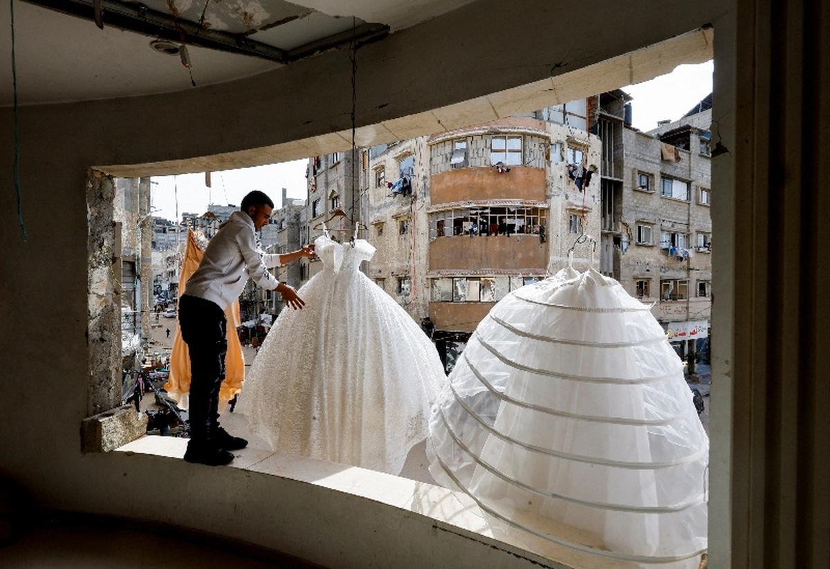 A Palestinian man hangs wedding dresses at a shop with damaged walls and ceiling, as brides in Gaza turn to reused gowns amid soaring prices and shortages caused by the war, in Khan Younis in the southern Gaza Strip, May 9, 2026. REUTERS/Mahmoud Issa
